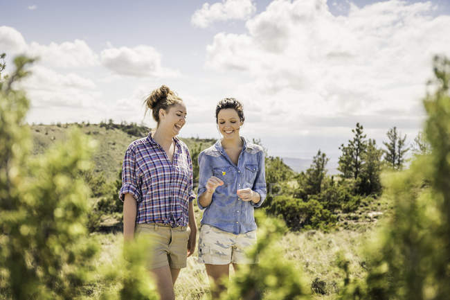 Zwei junge Frauen unterhalten sich beim Spazierengehen in Hügeln, Bridger, Montana, USA — Stockfoto