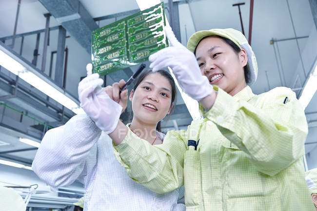 Supervisor overseeing work at quality check station at factory producing flexible electronic circuit boards. Plant is located in the south of China, in Zhuhai, Guangdong province — Stock Photo