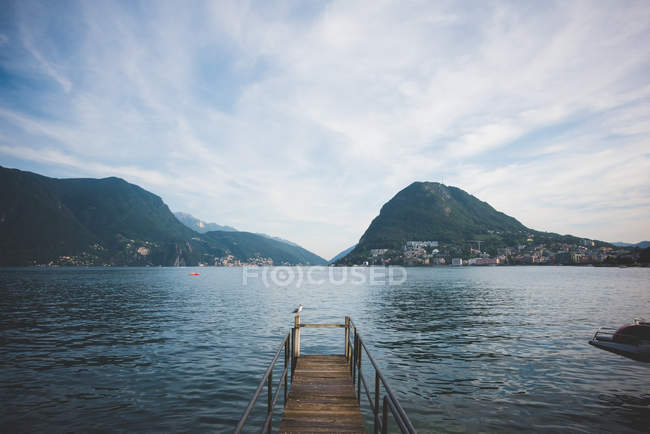 Cais de madeira no lago com vista para as montanhas — Fotografia de Stock