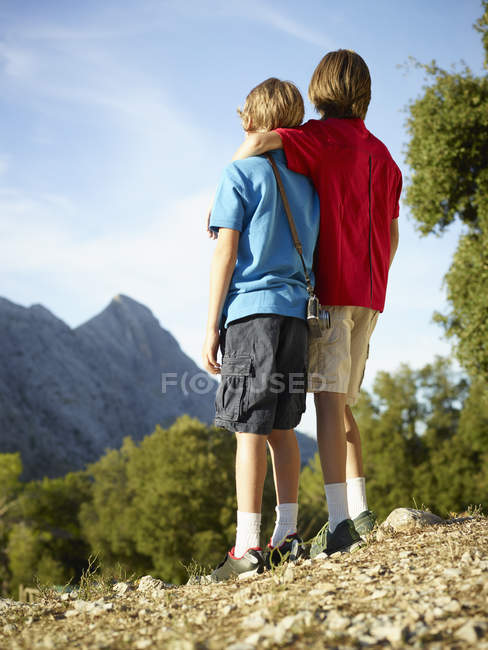 Вид сзади на двух братьев, собирающихся в горах, Майя, Испания — стоковое фото