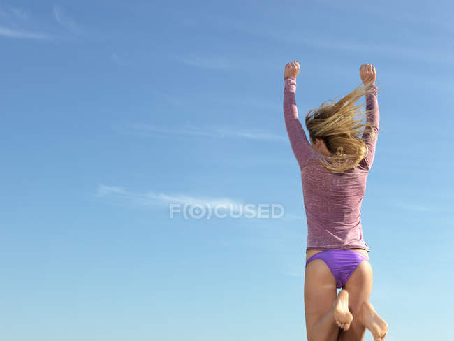 Rear view of young woman jumping mid air, Altona, Melbourne, Victoria, Australia — Stock Photo