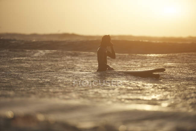 Silhouette of young male surfer and surfboard in sea, Devon, England, UK — Stock Photo