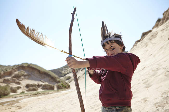 Young boy wearing fancy dress, holding home-made bow and arrow — Stock Photo