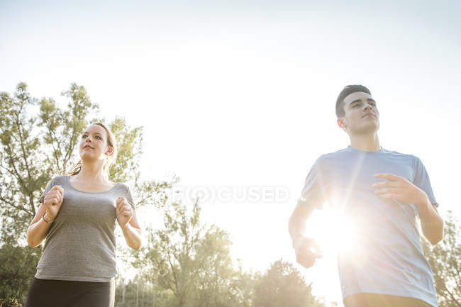 Dos adultos jóvenes, corriendo por el campo - foto de stock