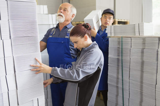 Trabalhadores da fábrica em movimento e empilhamento de papelão — Fotografia de Stock