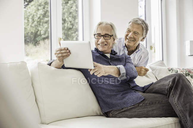 Dos hombres en casa, mirando la tableta digital - foto de stock