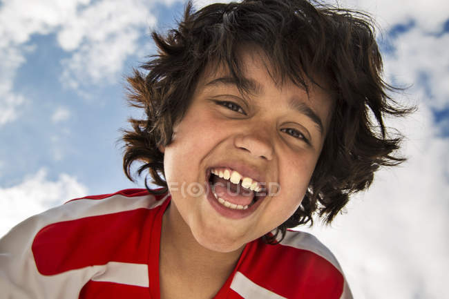 Низкоугольный портрет улыбающегося мальчика перед небом — стоковое фото