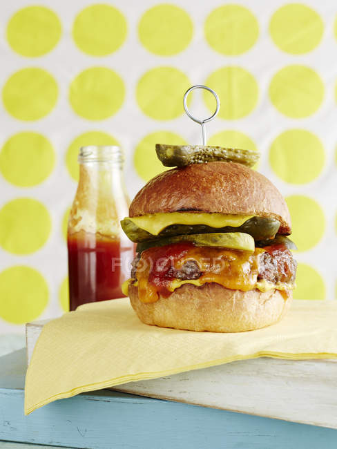 Cheeseburger con sottaceti e bottiglia di ketchup — Foto stock