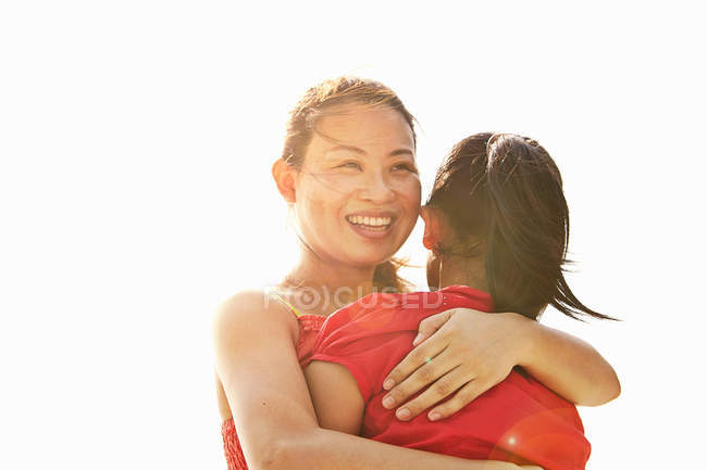 Retrato de una mujer sonriente abrazando a su hija - foto de stock