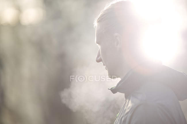 Vista lateral del hombre adulto medio mirando hacia otro lado, condensación de la respiración - foto de stock