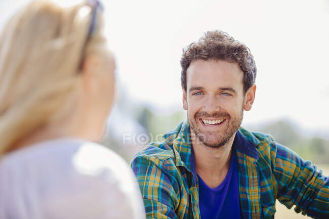 Sobre la vista del hombro del hombre adulto medio sentado sonriendo a la mujer joven - foto de stock