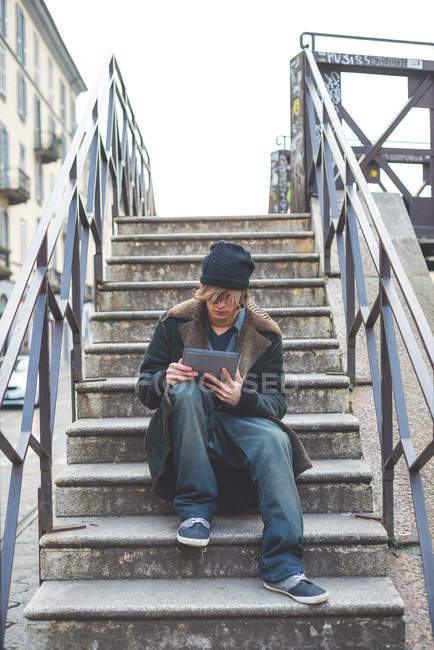 Man using digital tablet on steps, Milan, Italy — Stock Photo