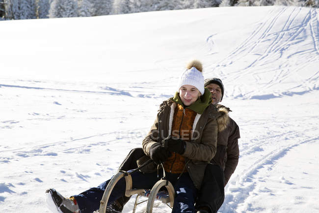 Senior couple sitting on sledge looking at camera and smiling, Sattelbergalm, Tyrol, Austria — Stock Photo