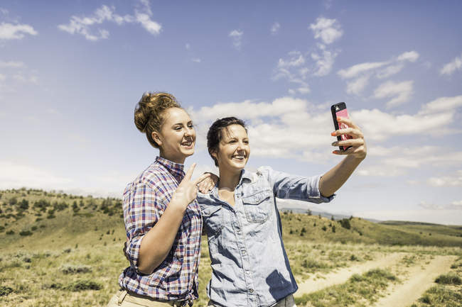 Дві молоді жінки, які беруть смартфон-селфі на брудний трек, Бріджер, Монтана, Уса. — стокове фото