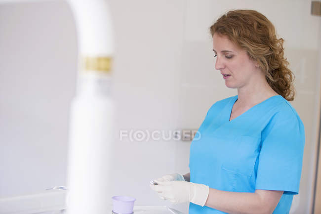 Infermiera dentale che indossa scrub e guanti protettivi preparare attrezzature dentali — Foto stock