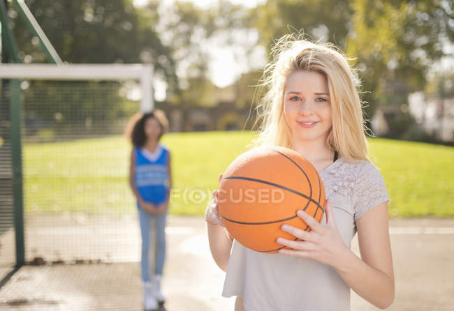 Portrait of young woman holding up basketball — Stock Photo