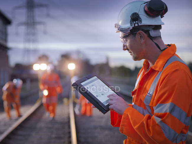Operatore di manutenzione ferroviaria che utilizza tablet digitale di notte a Loughborough, Inghilterra, Regno Unito — Foto stock