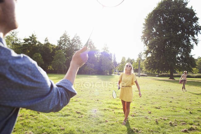 Young couple playing badminton in sunlit park — Stock Photo