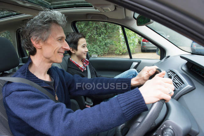 Uomo maturo guida auto con figlio adolescente — Foto stock