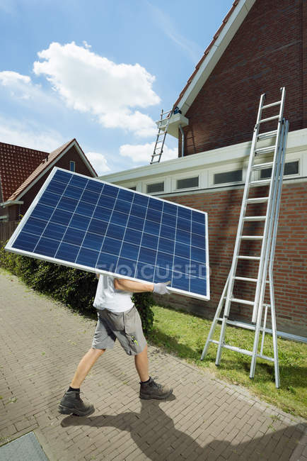 Lavoratore che trasporta pannello solare per tetto di casa, Paesi Bassi — Foto stock