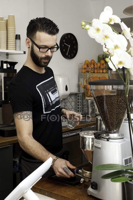 Cafe waiter preparing fresh coffee using machine behind counter — Stock Photo