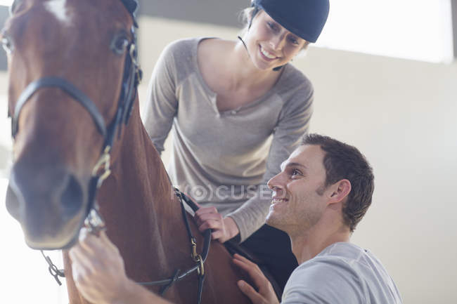 Giovane cavallerizza femminile con istruttrice in paddock indoor — Foto stock