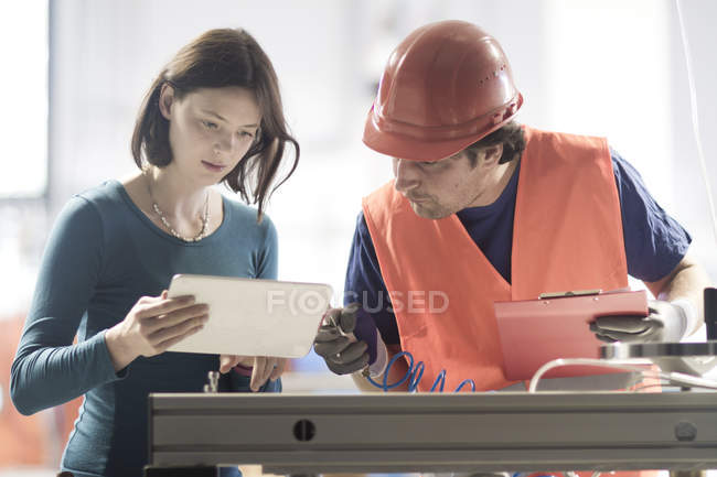 Male and female colleagues in industrial occupation using digital tablet — Stock Photo