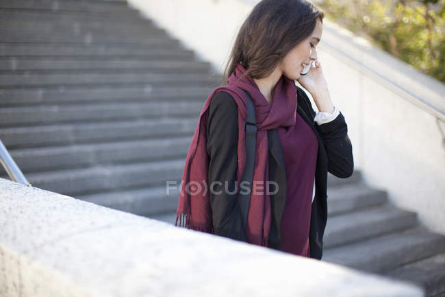 Young businesswoman chatting on smartphone on city stairway — Stock Photo