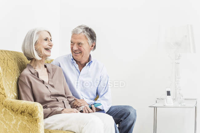 Старша пара розслабляється вдома, посміхаючись — стокове фото