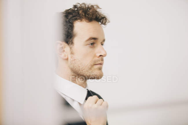 Young businessman fastening tie in apartment — Stock Photo