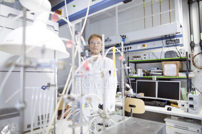 Retrato de un joven científico detrás de un experimento de laboratorio - foto de stock