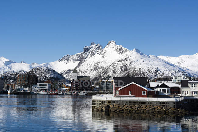 Vista de casas frente al mar y montañas nevadas - foto de stock