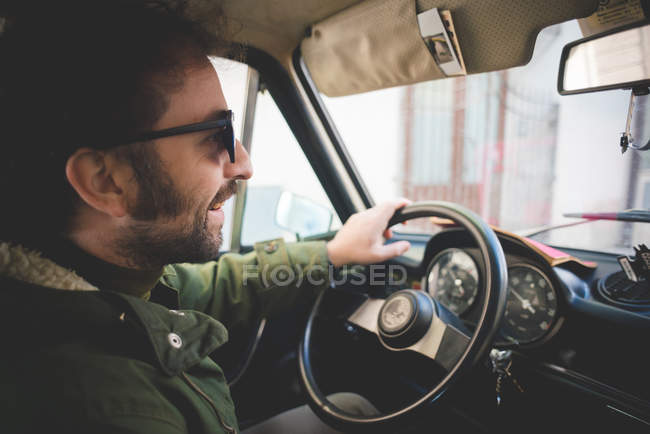Взрослый мужчина улыбается во время вождения винтажного автомобиля — стоковое фото