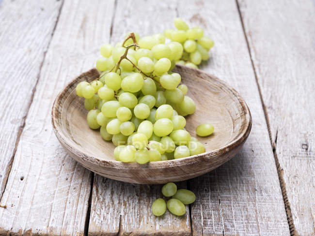 Grapes in wooden bowl on rustic table — Stock Photo