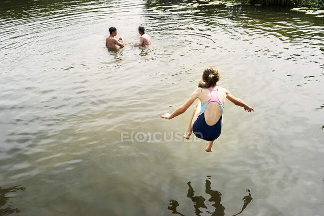 Вид сзади на девушку, прыгающую в озеро — стоковое фото