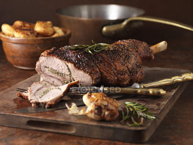 Roasted rosemary and garlic leg of lamb and roast potatoes — Stock Photo