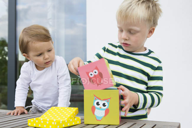 Boy and female toddler playing with building blocks on patio — Stock Photo