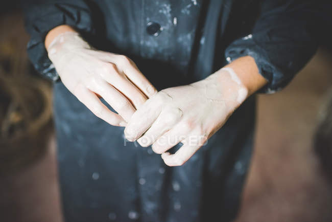 High angle cropped view of young woman clay covered hands — Stock Photo