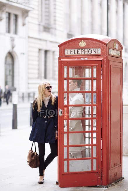 Parejas jóvenes en la cabina del teléfono rojo, Londres, Inglaterra, Reino Unido - foto de stock
