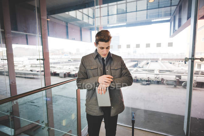 Portrait of young businessman commuter checking wristwatch for time. — Stock Photo