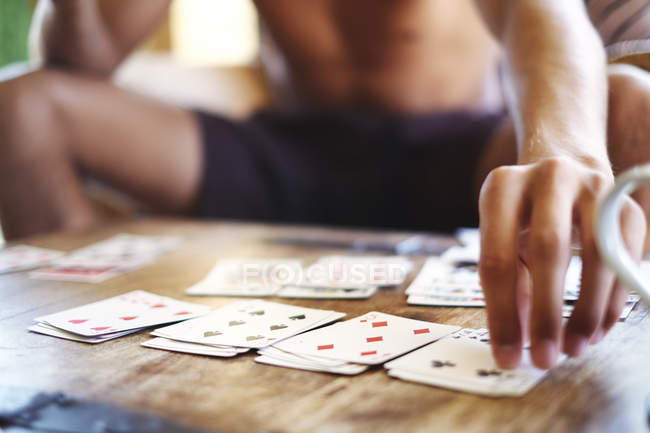 Cropped shot of young man playing cards at table — Stock Photo