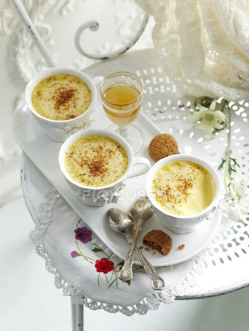 Baked custards in teacups on tray with spoons — Stock Photo