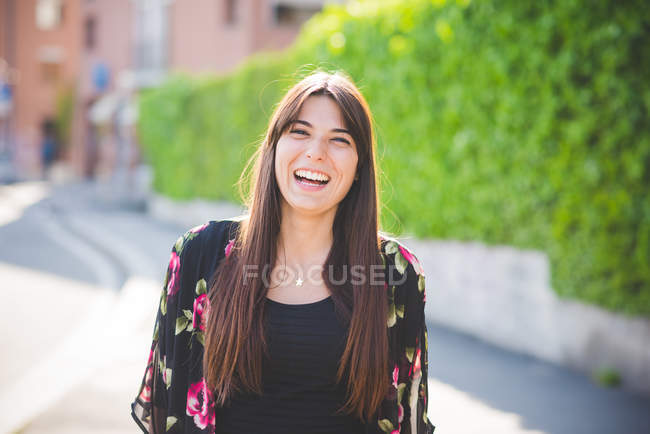 Портрет молодой женщины с длинными каштановыми волосами, смеющейся — стоковое фото