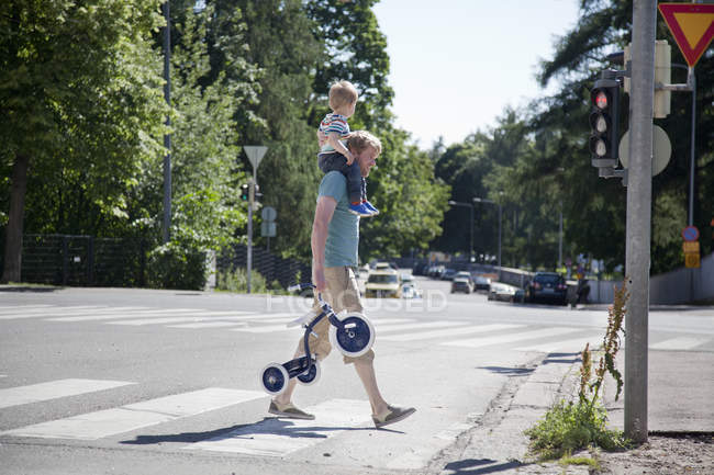 Father shoulder carrying toddler son over pedestrian crossing — Stock Photo