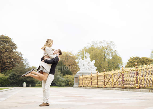 Romantic young man lifting up girlfriend in park — Stock Photo