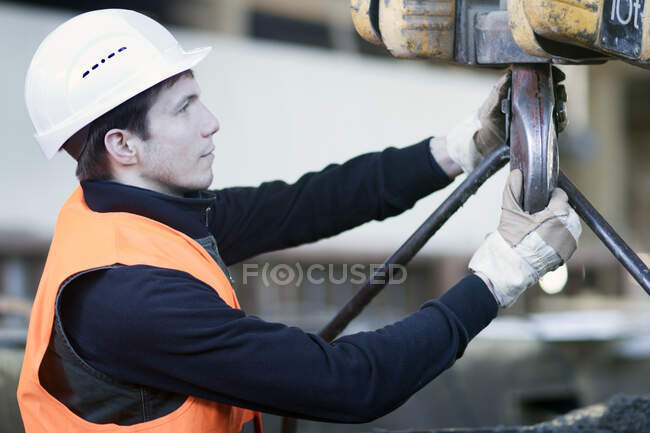 Arbeiter befestigt Seilwinde in Betonbewehrungsfabrik — Stockfoto