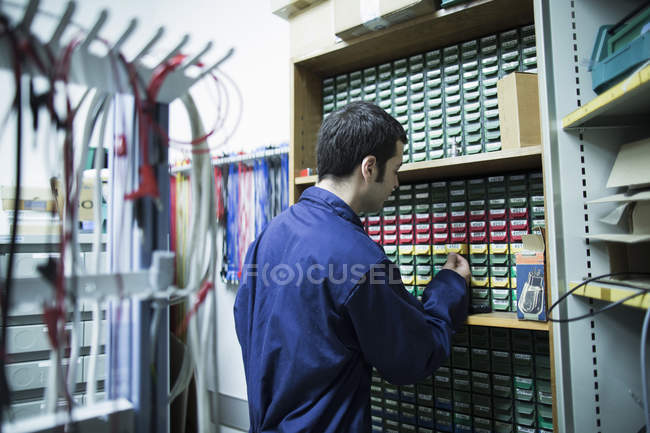 Elettricista maschio che seleziona attrezzature dai cassetti in officina — Foto stock