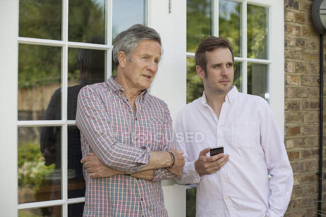 Adult father and son, standing together, talking, outdoors — Stock Photo