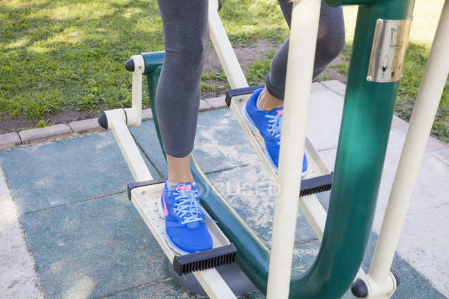 Plan recadré de jambes féminines s'entraînant sur la machine pas à pas dans le parc — Photo de stock