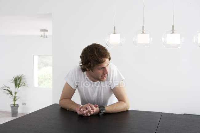 Nachdenklicher junger Mann sitzt am Esstisch — Stockfoto